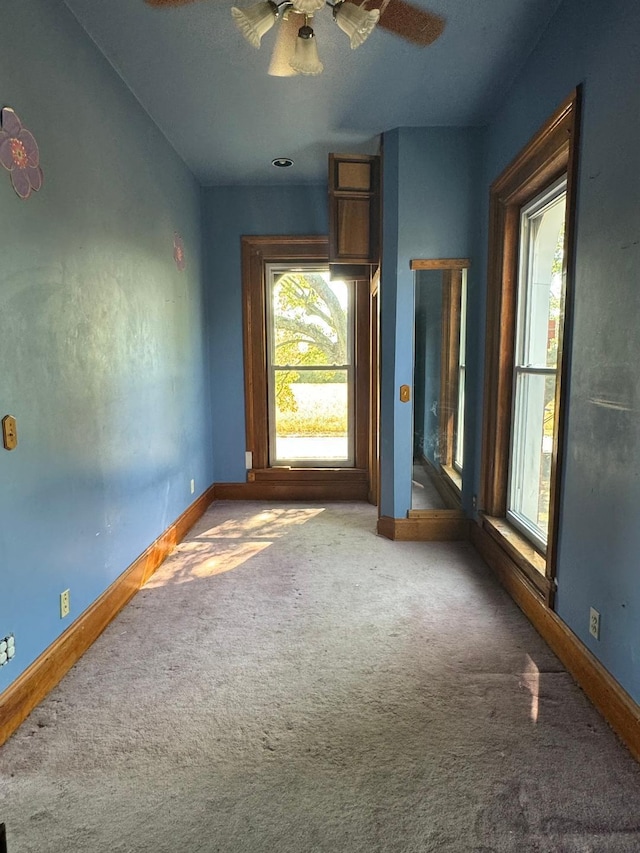 carpeted spare room with a ceiling fan and baseboards