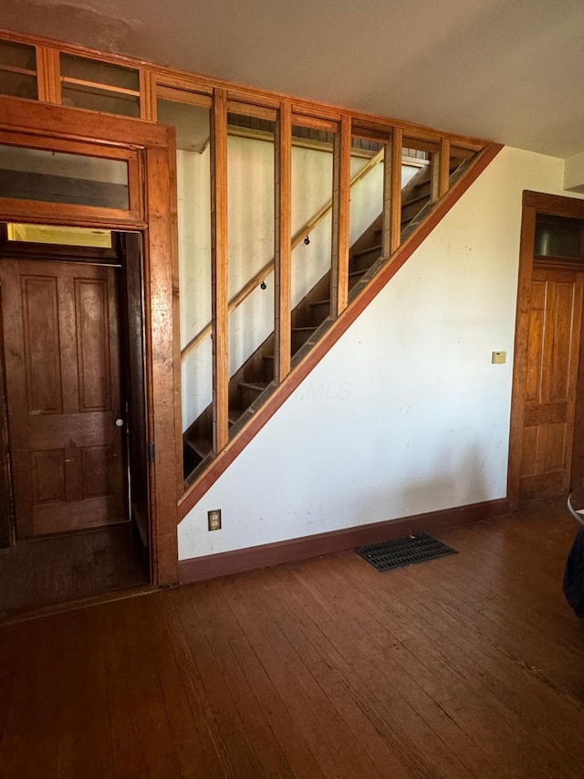 stairs with wood-type flooring, visible vents, and baseboards