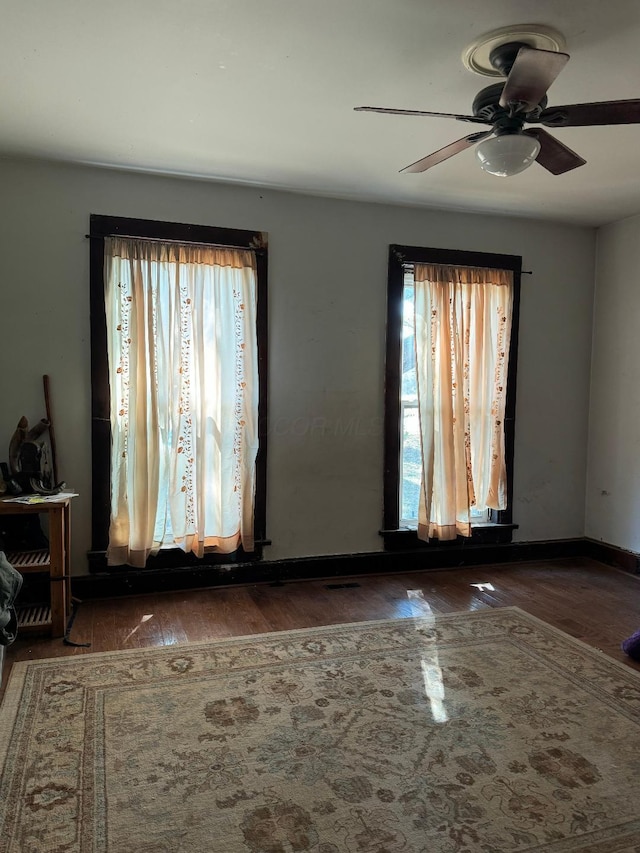 unfurnished room featuring wood finished floors, a wealth of natural light, and a ceiling fan