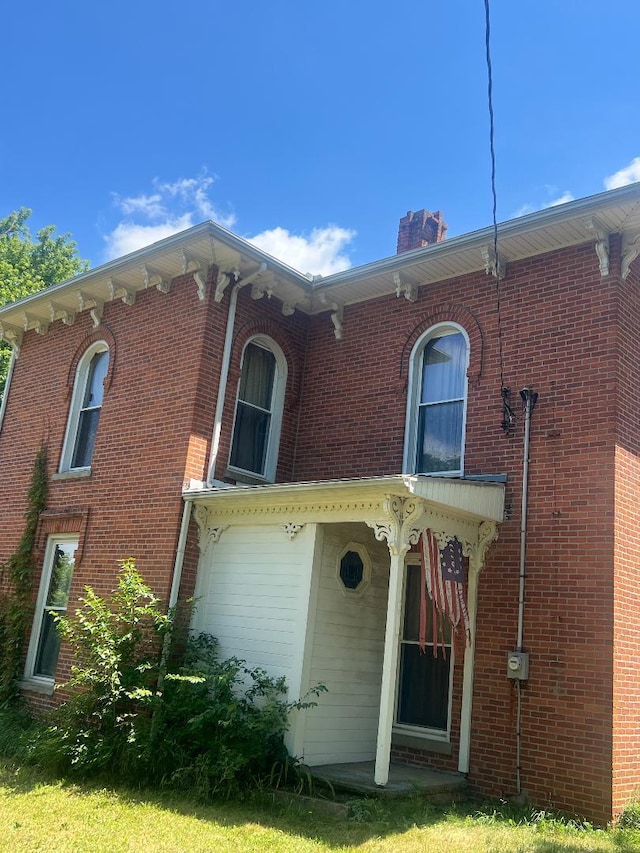 back of house featuring brick siding and a chimney