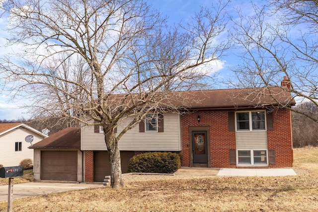 raised ranch with a garage, concrete driveway, brick siding, and a chimney