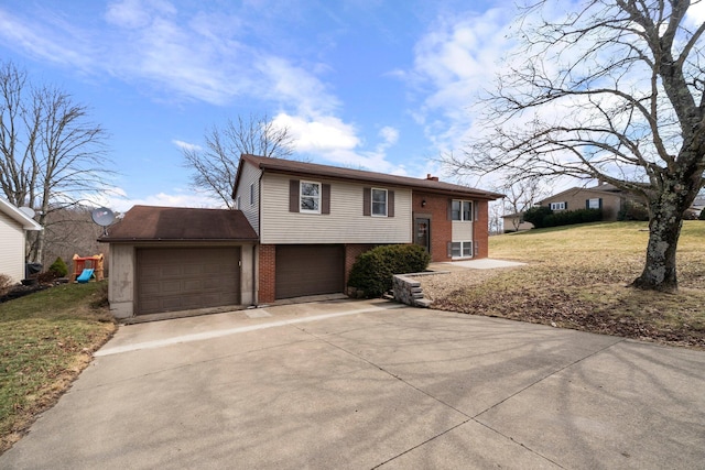 raised ranch with brick siding, a chimney, a garage, driveway, and a front lawn