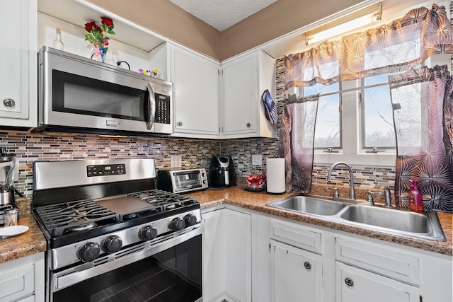 kitchen with a toaster, decorative backsplash, appliances with stainless steel finishes, white cabinets, and a sink