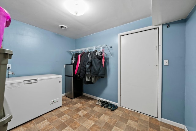 laundry room featuring baseboards, laundry area, visible vents, and stone finish flooring