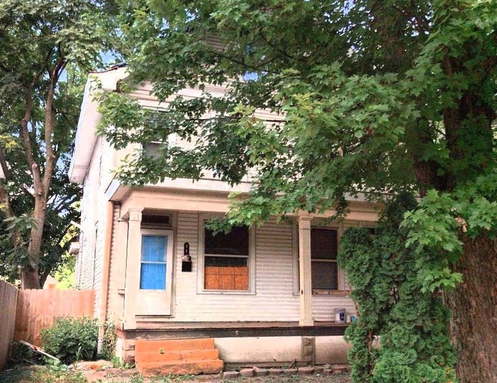 view of front facade featuring covered porch and fence