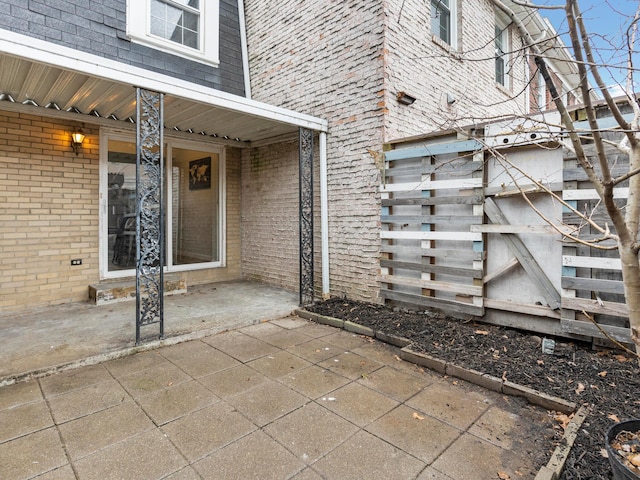 entrance to property featuring a patio area and brick siding