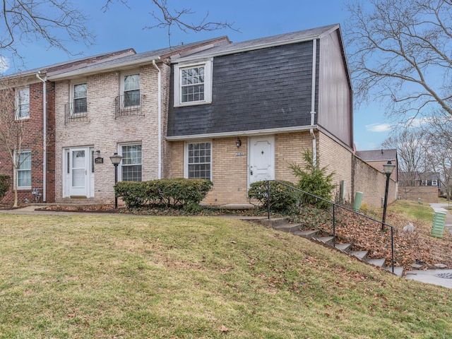 view of front of house featuring brick siding, a front lawn, and roof with shingles