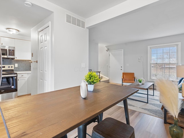 dining space featuring light wood-type flooring and visible vents