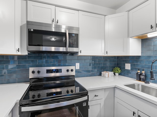 kitchen with stainless steel appliances, white cabinets, light countertops, and backsplash