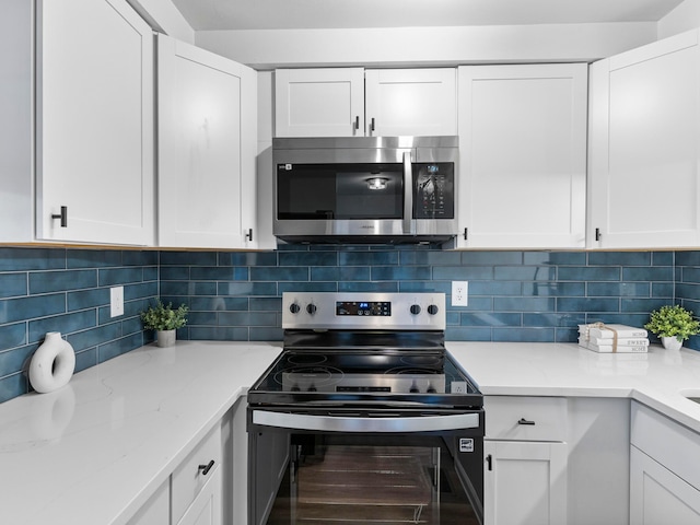 kitchen featuring appliances with stainless steel finishes, light stone countertops, white cabinets, and tasteful backsplash