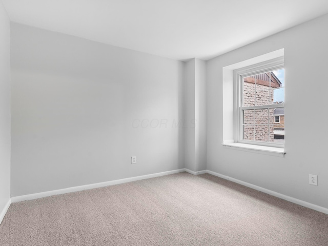 carpeted empty room featuring baseboards