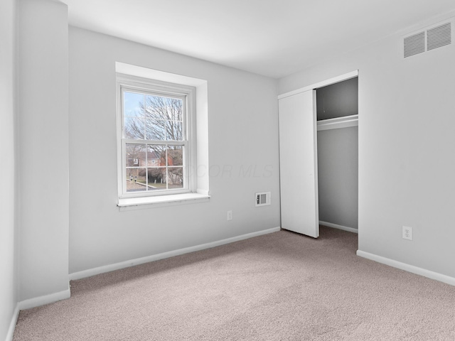 unfurnished bedroom featuring carpet floors, baseboards, visible vents, and a closet