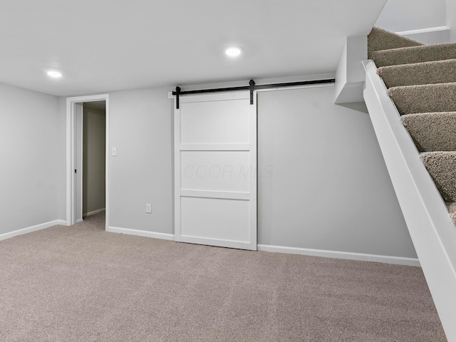 below grade area featuring a barn door, recessed lighting, carpet flooring, baseboards, and stairway