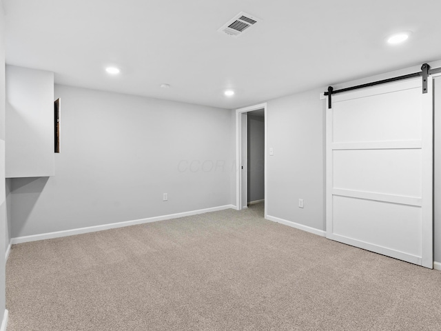 basement with carpet floors, recessed lighting, visible vents, a barn door, and baseboards