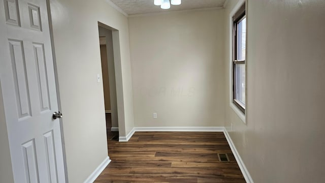 corridor with dark wood finished floors, visible vents, crown molding, and baseboards