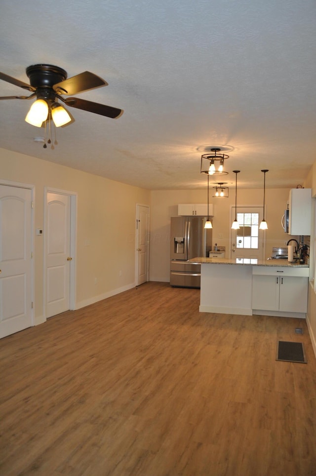 kitchen with a peninsula, light wood finished floors, stainless steel refrigerator with ice dispenser, and a ceiling fan