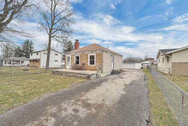 view of front facade with an outbuilding, fence private yard, a garage, a chimney, and a front yard