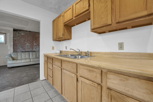 kitchen with light tile patterned floors, light countertops, a sink, and light colored carpet