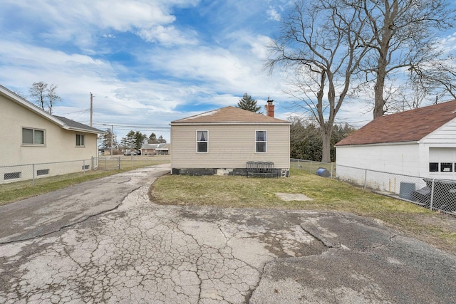 view of property exterior featuring a lawn, a chimney, and fence