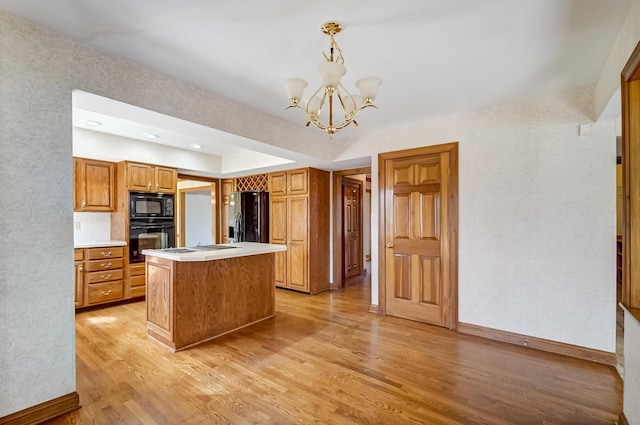 kitchen with brown cabinets, black appliances, light countertops, light wood-type flooring, and a center island