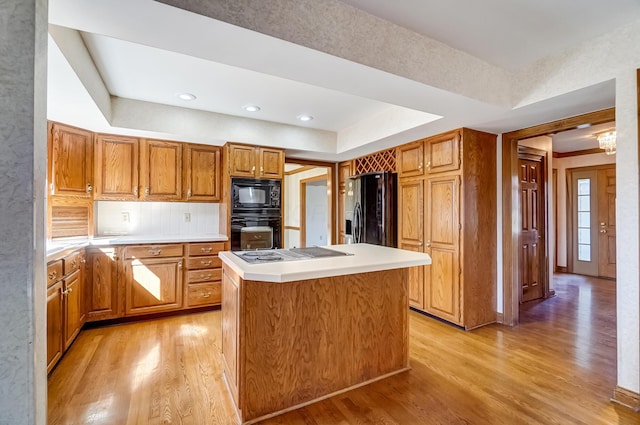 kitchen featuring black appliances, light wood-style flooring, light countertops, and a center island