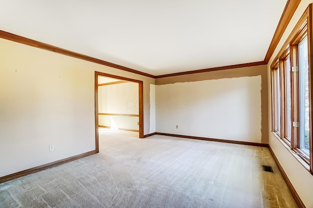 empty room with visible vents, baseboards, light colored carpet, and crown molding