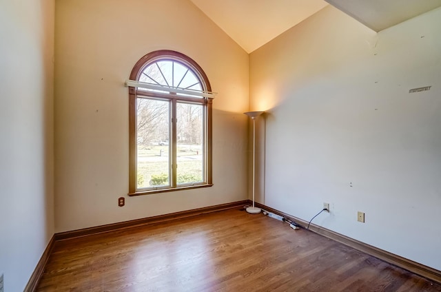 spare room with lofted ceiling, wood finished floors, and baseboards