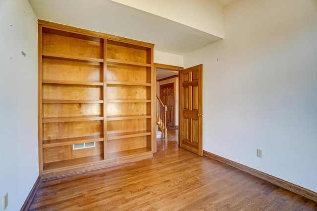 spare room featuring visible vents, baseboards, and wood finished floors