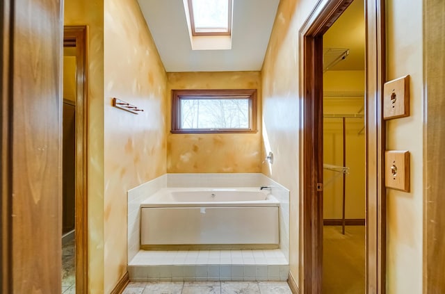 full bathroom with a skylight and a bath