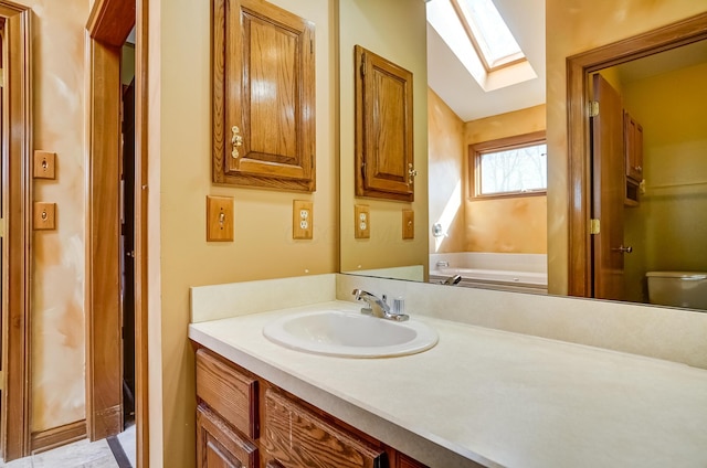 full bathroom featuring a bathing tub, toilet, lofted ceiling with skylight, and vanity