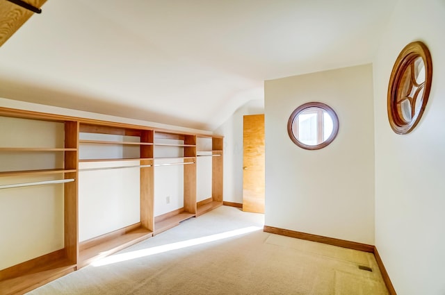 unfurnished bedroom with light carpet, visible vents, baseboards, and lofted ceiling