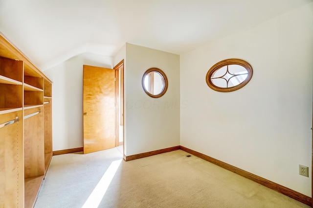 additional living space featuring vaulted ceiling, light colored carpet, and baseboards