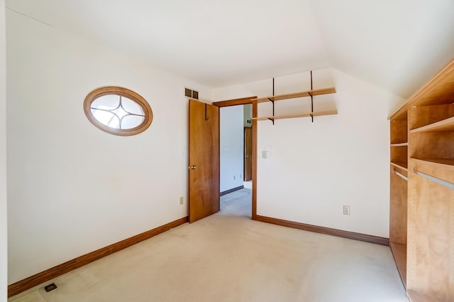 spare room with vaulted ceiling, baseboards, visible vents, and light carpet