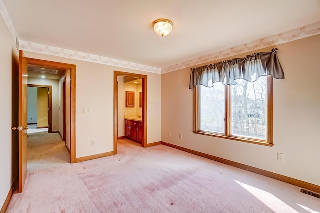 unfurnished bedroom with visible vents, baseboards, light carpet, and ensuite bath