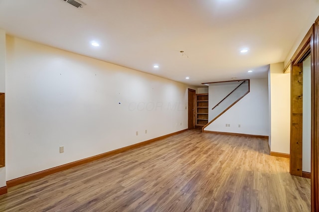 below grade area with recessed lighting, baseboards, light wood-style flooring, and stairs