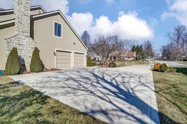 view of side of property featuring a garage, driveway, and stucco siding