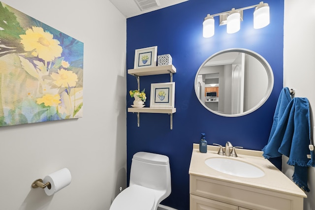 half bath with toilet, visible vents, and vanity