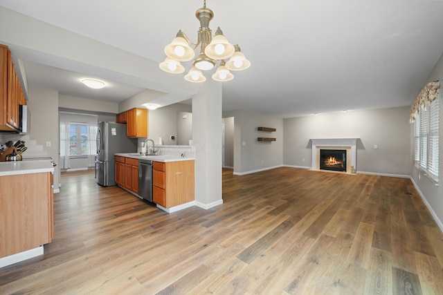 kitchen with stainless steel appliances, open floor plan, light countertops, and wood finished floors