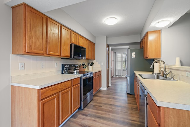 kitchen featuring light countertops, appliances with stainless steel finishes, a sink, and tasteful backsplash