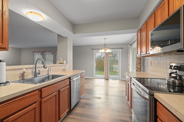 kitchen with appliances with stainless steel finishes, light countertops, a sink, and backsplash