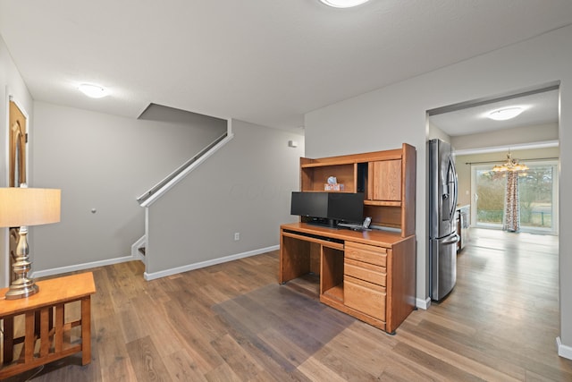 office area featuring light wood-type flooring, an inviting chandelier, and baseboards