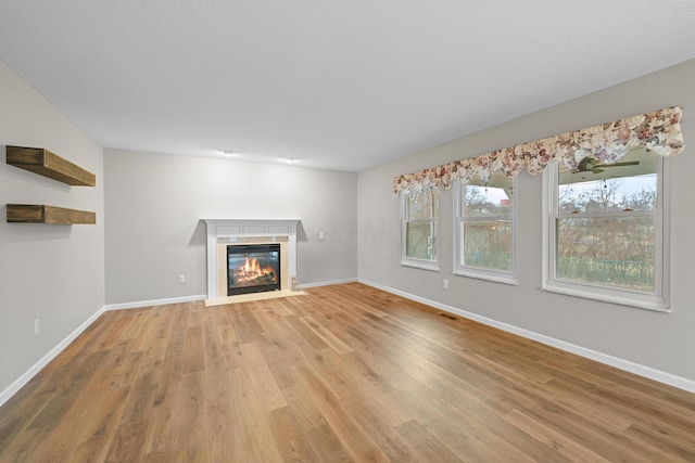 unfurnished living room featuring visible vents, a fireplace with flush hearth, light wood-style flooring, and baseboards