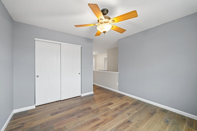 unfurnished bedroom featuring a closet, ceiling fan, baseboards, and wood finished floors