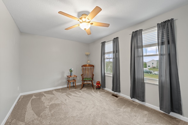 unfurnished room with carpet floors, ceiling fan, a textured ceiling, and baseboards