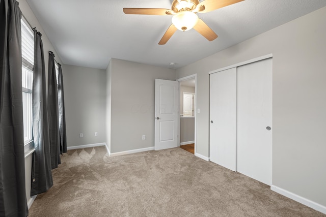 unfurnished bedroom featuring a closet, carpet, a ceiling fan, and baseboards