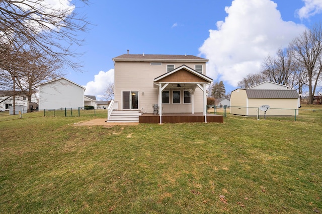 rear view of house with ceiling fan, a lawn, and fence