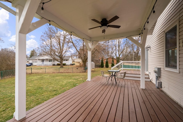 wooden deck featuring a ceiling fan, a fenced backyard, and a lawn