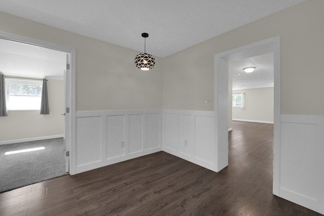 empty room with a wainscoted wall and dark wood finished floors