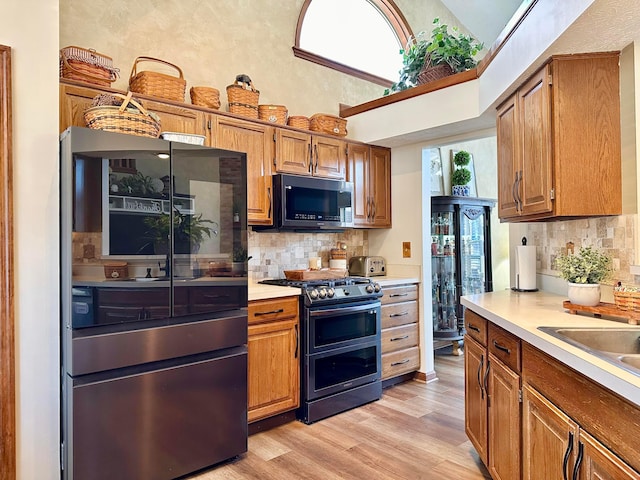 kitchen featuring stainless steel appliances, light countertops, light wood-style flooring, and tasteful backsplash