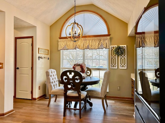 dining area featuring a chandelier, vaulted ceiling, a textured ceiling, and wood finished floors